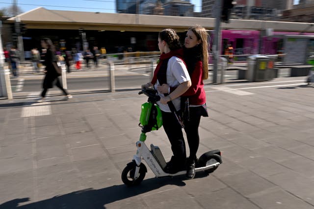 <p>People ride a rental e-scooter in Melbourne on 13 August 2024</p>