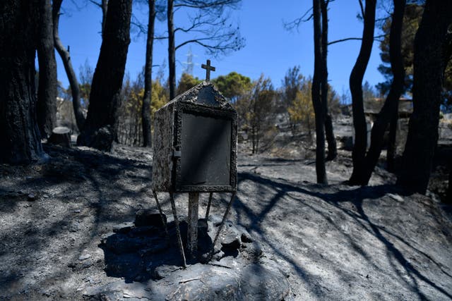 <p>A burned roadside shrine stands in Nea Penteli suburb of Athens, on Tuesday</p>