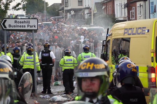 <p>Riot police hold back protesters after disorder broke out in Southport</p>