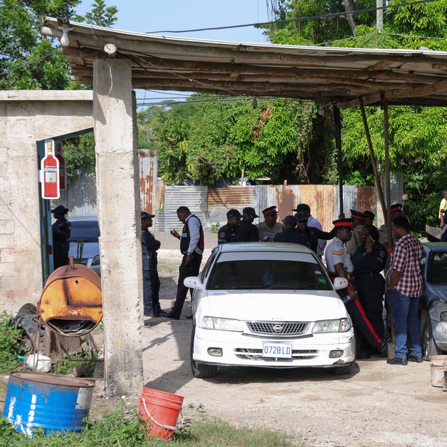 <p>Jamaican officials work at a crime scene in Clarendon, Jamaica on Wednesday after gunmen opened fire at a birthday party, killing seven before an eighth victim died in a separate shooting</p>