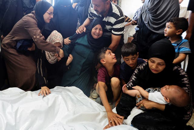 <p>People mourn next to the bodies of Palestinians killed in Israeli strikes at Al-Aqsa Martyrs Hospital in Gaza</p>