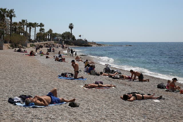 <p>FILE PHOTO: People enjoy the beach following the easing of measures against the spread of the coronavirus disease (COVID-19) in Faliro suburb, near Athens, Greece, April 3, 2021</p>