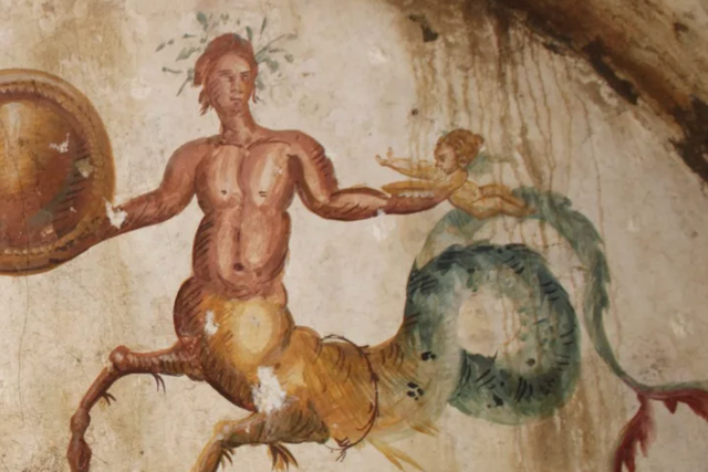 <p>Tomb has a painting of two sea-centaurs holding a circular shield next to two babies</p>